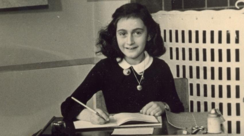 Anne Frank sits at a desk in 1940.